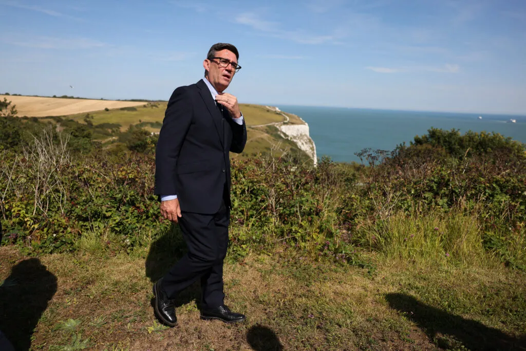 Andy Burnham marche près des falaises de Douvres en Angleterre pendant une visite au centre de coordination des secours maritimes de la HM Coastguard le 2 août 2026.